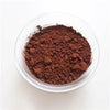 A glass dish of cocoa powder sitting on a white table.