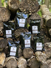 Bags of coffee that are laid across a wood pile.